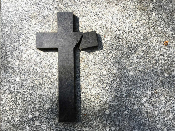 Broken black cross on a gray surface