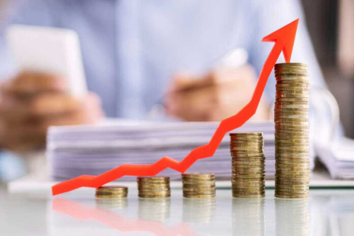 Stacked coins with upward red arrow graph in foreground