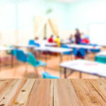 Blurred classroom with students and a wooden foreground