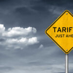 Tariff Bombshell Shakes Truck Industry Yellow sign saying tariffs just ahead cloudy sky