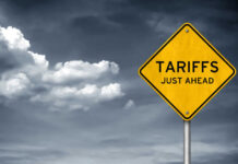 Yellow sign saying tariffs just ahead cloudy sky