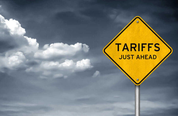 shutterstock_1037228893.jpg Yellow sign saying tariffs just ahead cloudy sky