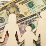 Wooden figures representing a family on a background of US dollar bills