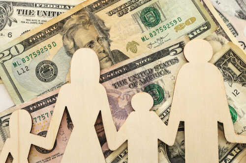 Wooden figures representing a family on a background of US dollar bills