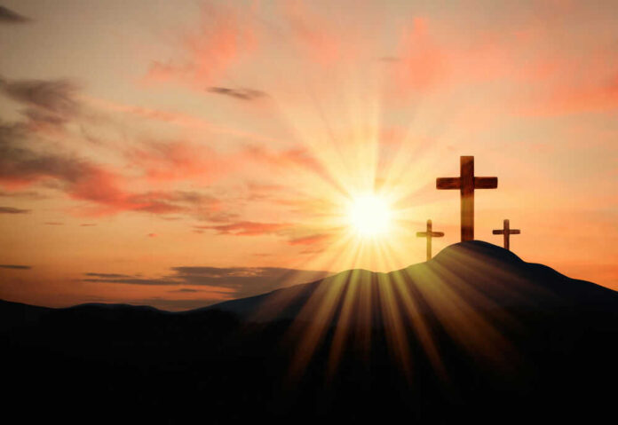 Three crosses on a hill, sunrise background.