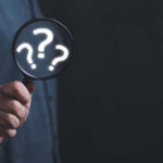 Pearl Harbor Mystery Solved! Hand holding magnifying glass with question marks