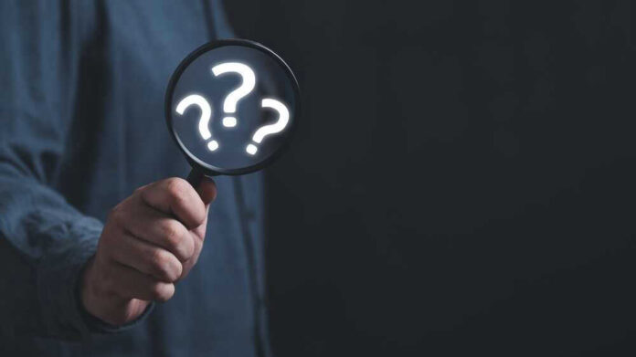 shutterstock_2278136667.jpg Hand holding magnifying glass with question marks