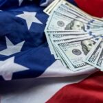 $1 Trillion Demand Holds Government Hostage Stack of hundred dollar bills on an American flag