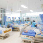 Blurred hospital room with multiple patients and nurses