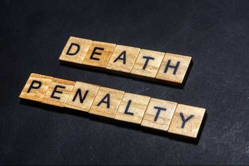 shutterstock_2389190169.jpg Wooden letter tiles spelling DEATH PENALTY on a dark background