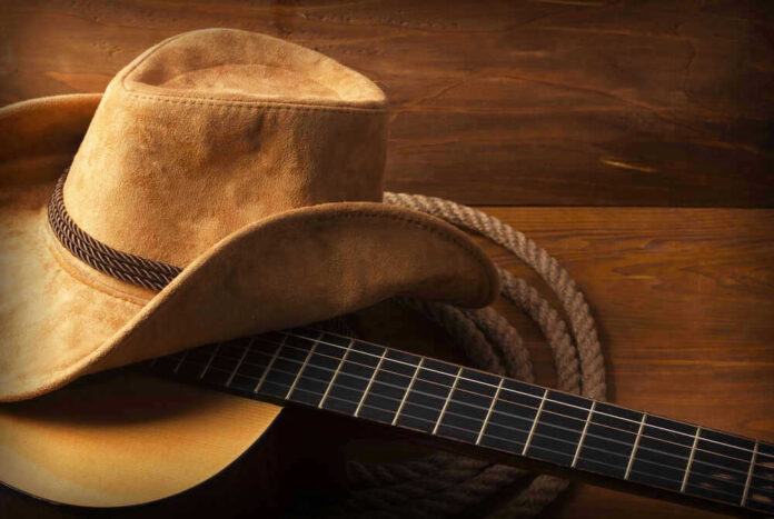 Cowboy hat on guitar next to coiled rope.