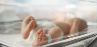 Newborn baby in hospital bassinet with ID band.