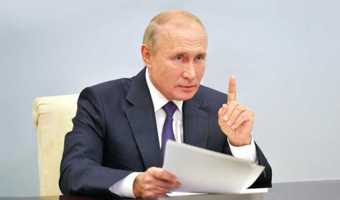 Vladimir Putin, holding papers, in a meeting.
