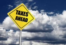 Energy Tax Plan Sparks Panic Yellow road sign reading taxes ahead clouds background