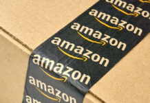 Amazon’s AI Gamble — Engineers Axed By The Thousands Close-up of an Amazon-branded shipping box tape on a cardboard box