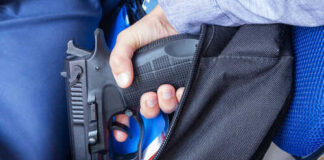 A hand holding a gun inside a backpack