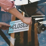 Person flipping closed sign on glass door