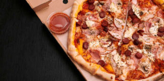 A pizza with various toppings in a delivery box