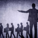 Shadows of laid-off workers walking, large figure pointing.