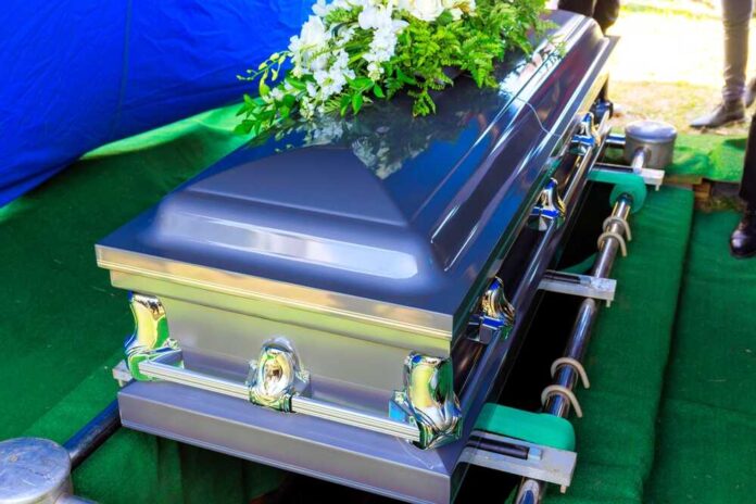 shutterstock_2607928955.jpg A silver casket adorned with flowers at a gravesite