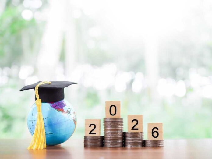 Globe with a graduation cap next to stacks of coins and wooden blocks displaying the year 2026