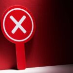 Stunning Revision Wipes Out Job Boom Red sign with a white 'X' symbol against a dark background