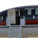 Trump Trademark Move Targets Airport Person waving from the doorway of an airplane