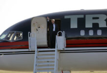 Person waving from the doorway of an airplane