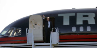 Person waving from the doorway of an airplane