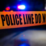 Illegal Gun Sale Sparks Deadly Terrorist Classroom Rampage Police tape with flashing lights in the background.