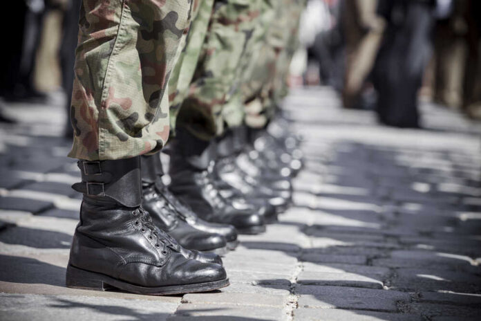 Row of soldiers in black boots and camouflage pants standing in formation