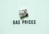 A bundle of cash next to the words 'GAS PRICES' on a light green background