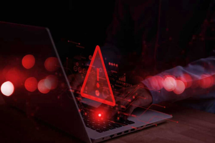 Warning symbol over laptop with user.