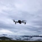 Drone Attack Slams World’s Biggest LNG A drone flying against a cloudy sky over a mountainous landscape