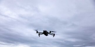 A drone flying against a cloudy sky over a mountainous landscape