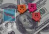 Colorful house icons on a background of hundred dollar bills with a downward trend graph