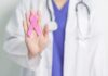 A healthcare professional holding a pink ribbon in their hand
