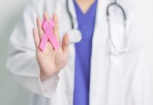 A healthcare professional holding a pink ribbon in their hand