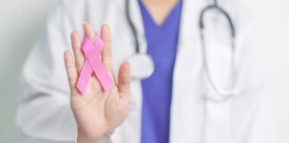 A healthcare professional holding a pink ribbon in their hand