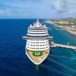 Cruise Outbreak Spirals — 153 Stricken A large cruise ship docked near a tropical coastline