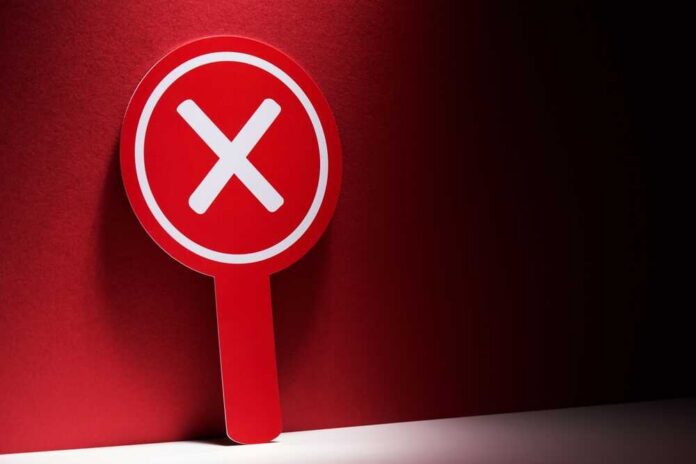 Red sign with a white 'X' symbol against a dark background