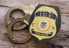 ICE officer badge next to handcuffs on a wooden surface