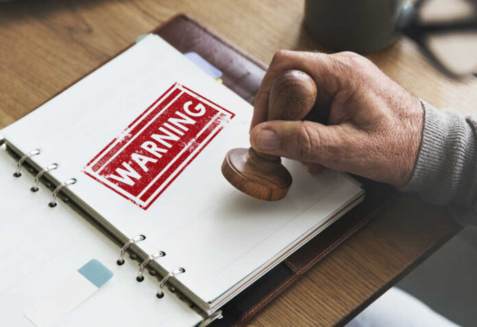 shutterstock_494536357.jpg A hand applying a warning stamp on a document