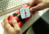 Hands holding a red explosive device with a timer on a desk