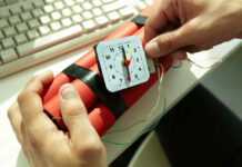 Hands holding a red explosive device with a timer on a desk