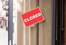 A red 'CLOSED' sign hanging on a storefront door