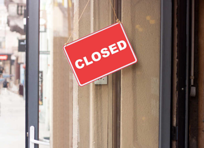 A red 'CLOSED' sign hanging on a storefront door