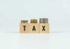 Blocks spelling 'TAX' with coins stacked beside them