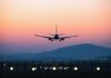 An airplane approaching for landing against a colorful sunset sky