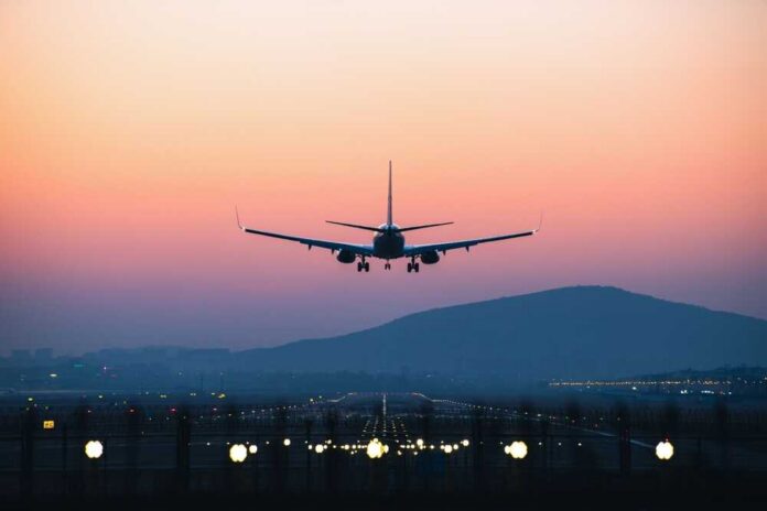 An airplane approaching for landing against a colorful sunset sky